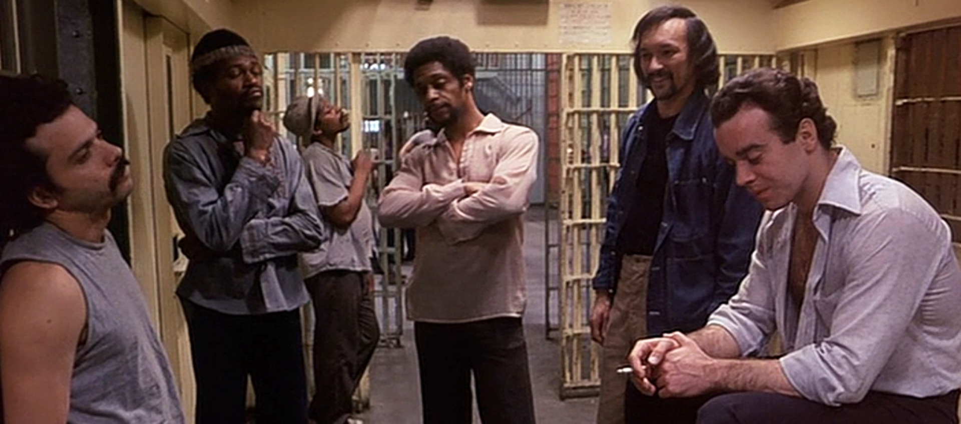 A group of men stand around a large prison cell.