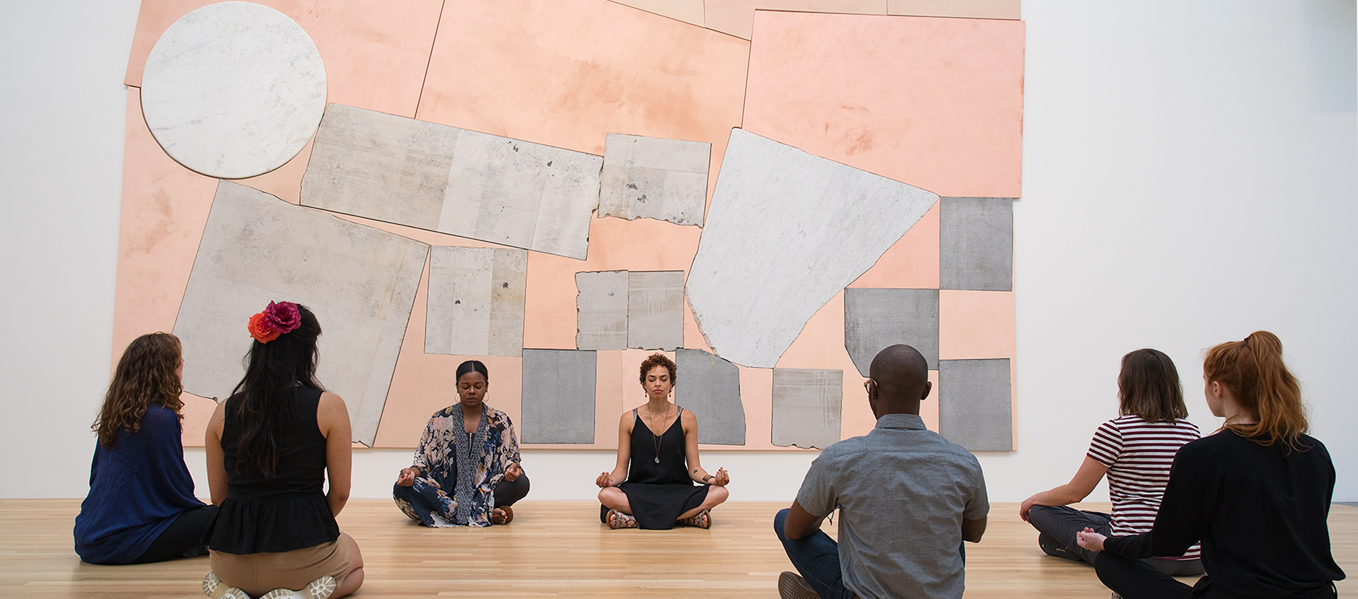 a group of people practicing yoga with an art work installation behind them