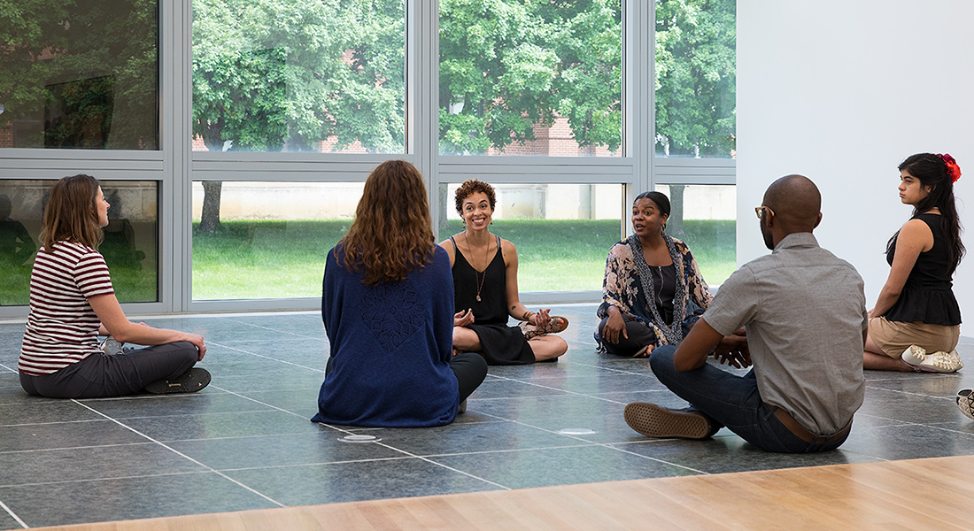 six people seated in yoga poses in the Wexncer Center gallery space
