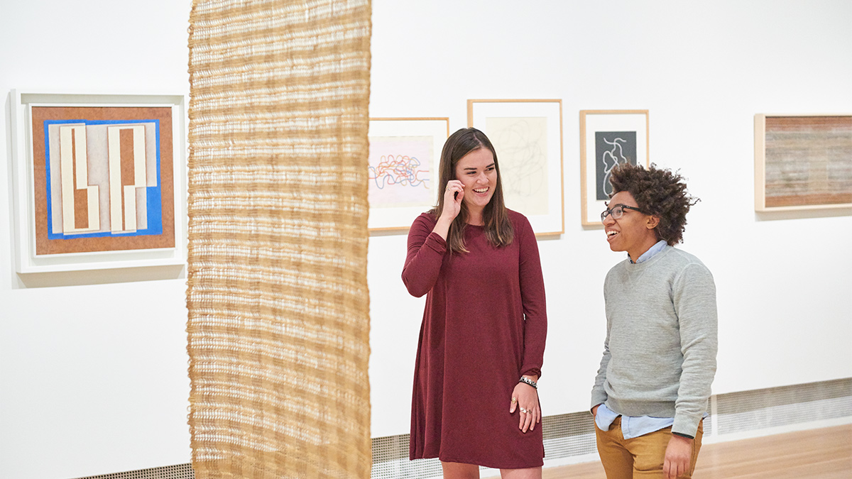 two patrons looking at a large woven tapestry in the Wexner Center galleries