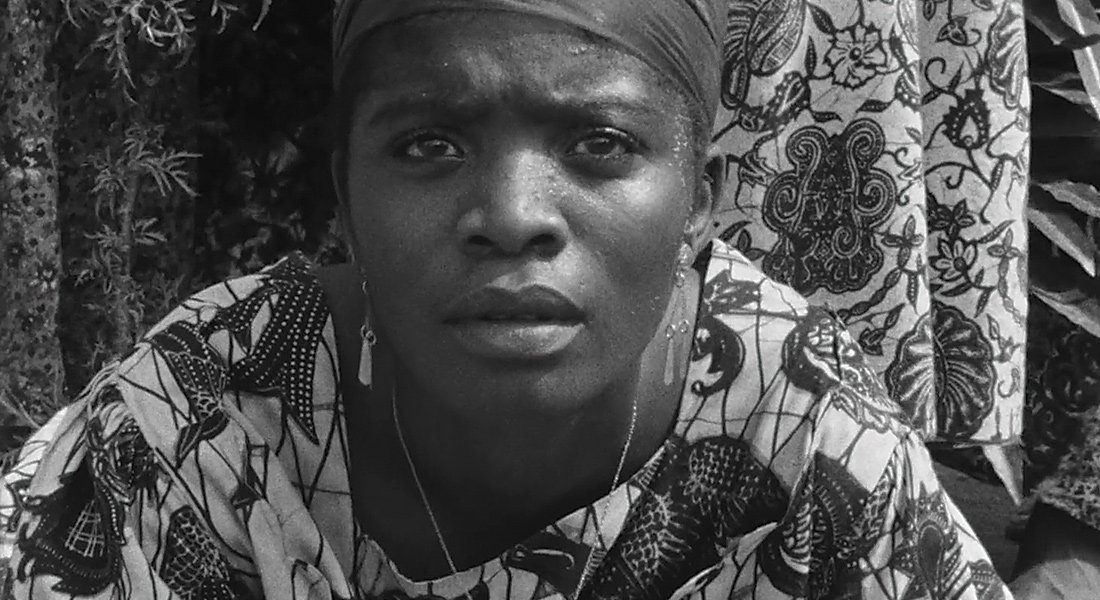 A black woman in close-up stares directly into the camera in a scene from the film Muna Moto