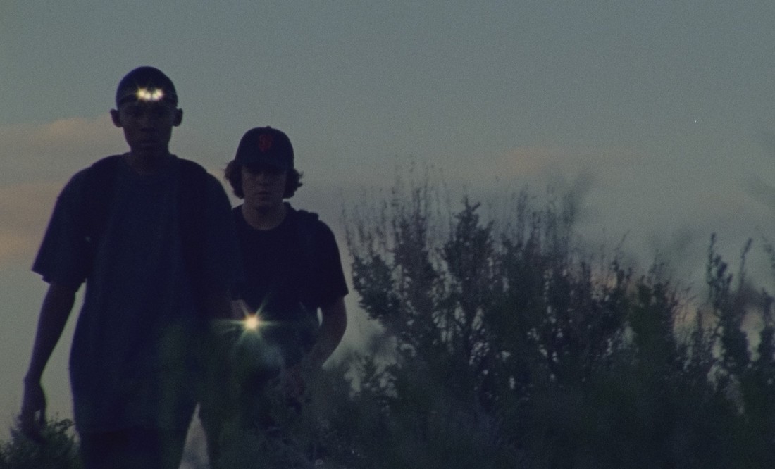 Two teenage boys with flashlights walk toward the camera in a scene from Stanya Kahn's short film No Go Backs