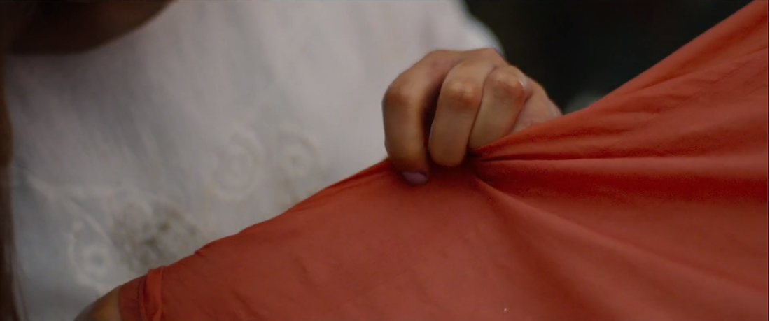 A hand tugs at a piece of cloth in a scene from the film Papicha