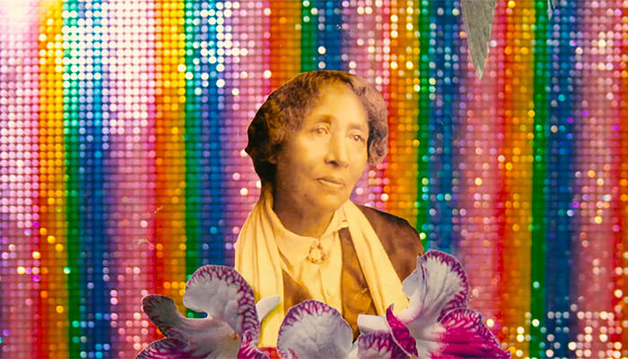 A vintage sepia image of a woman holding white and violet orchids against a sequined rainbow background