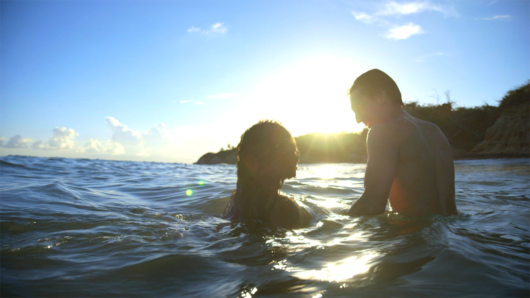 Two people laugh and swim in the sea.