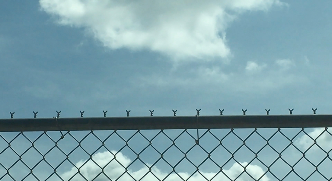 A chain link fence in front of a blue sky