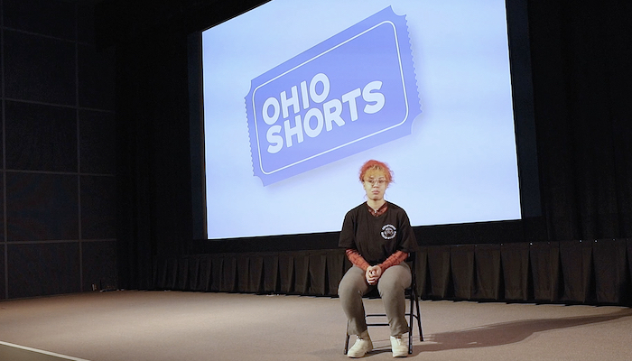 2022 Ohio Shorts guest juror Reg Zehner sits in a chair on the stage of the Wex's Film/Video Theater