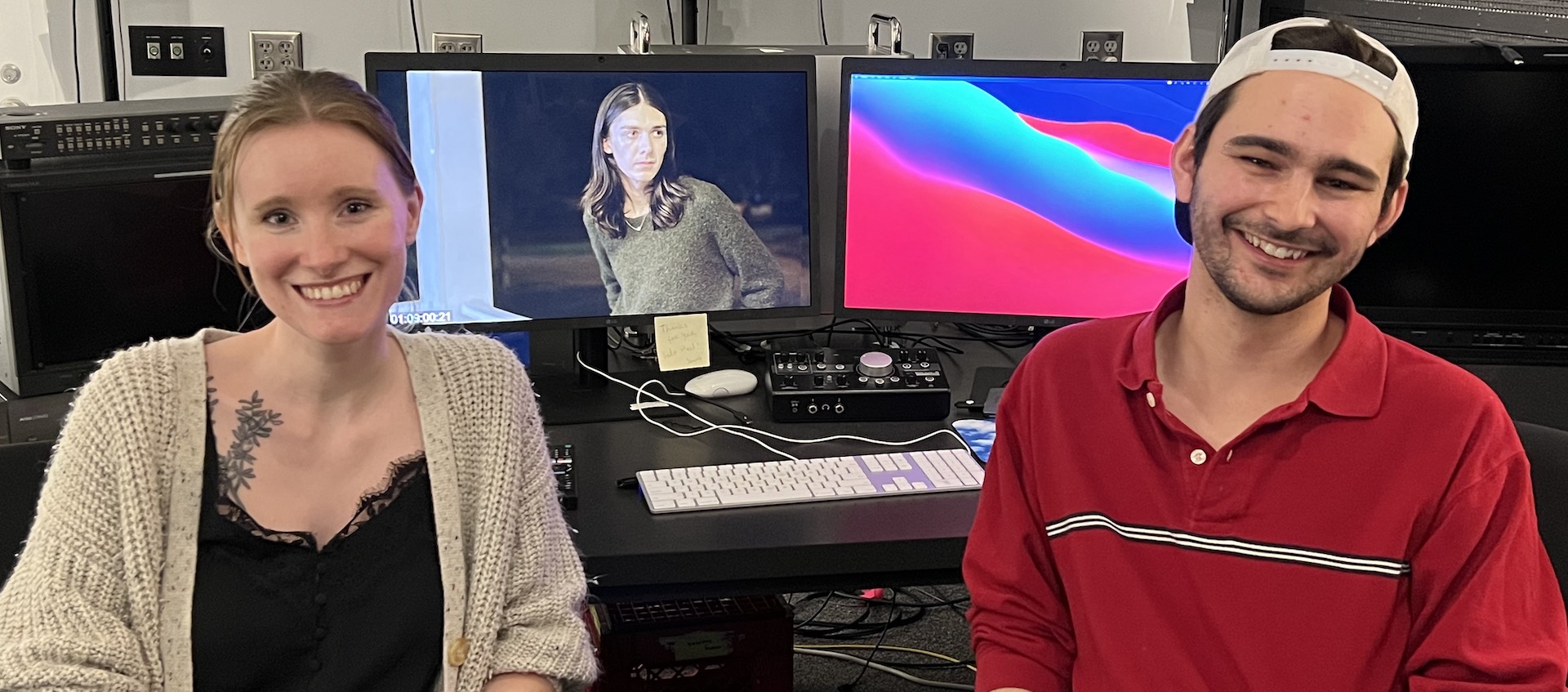 Filmmakers Hannah Blair and Ben Evory sitting in front of two monitors in an editing suite in the Wexner Center Film/Video Studio