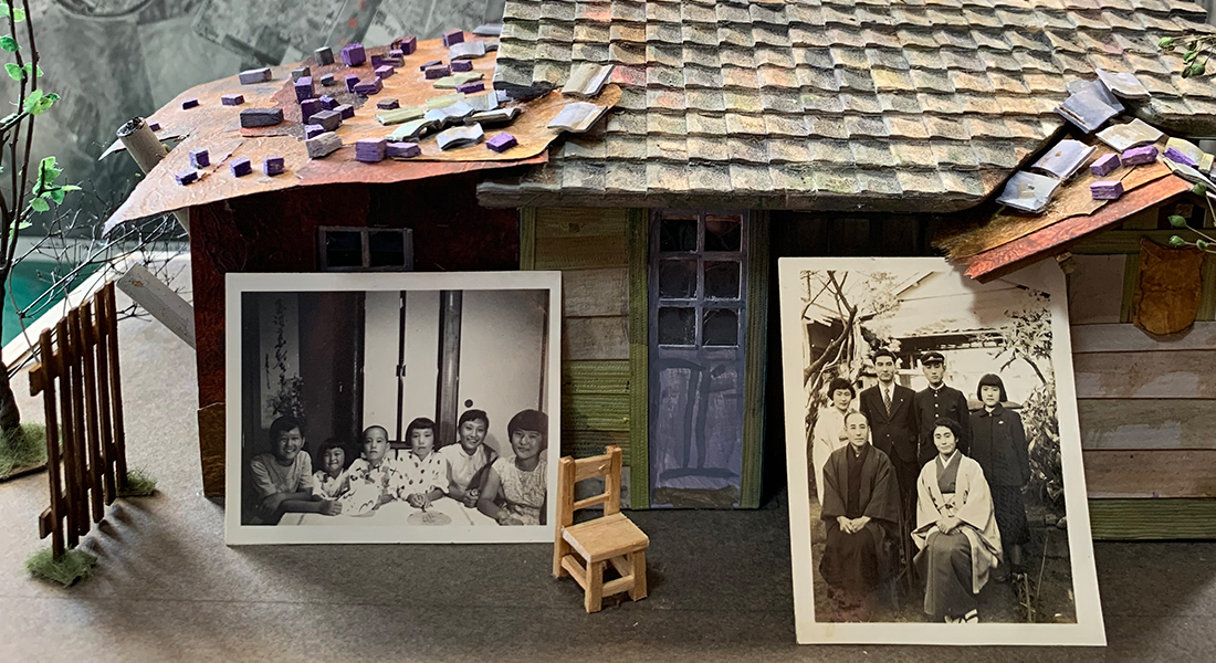 Two black-and-white photos of groups of people lie against a model of a house